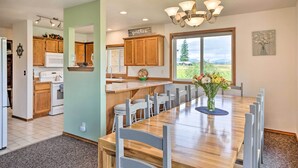 A modern kitchen with wooden cabinets, a central island with bar stools, and a dining area with a large wooden table and chairs. - 51 Mi to Mt Rainier: Mtn-View Escape on 8 Acres! (Randle)