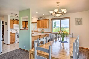 A kitchen with wooden cabinets, a white refrigerator, and a large dining table with chairs. - 51 Mi to Mt Rainier: Mtn-View Escape on 8 Acres! (Randle)