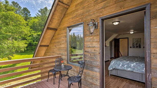 A wooden cabin with a balcony, a bed, and a dining area. - 51 Mi to Mt Rainier: Mtn-View Escape on 8 Acres! (Randle)