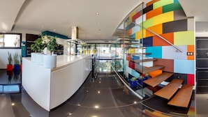 Eine moderne Küche mit einer gewölbten Kochinsel, einer Treppe mit farbenfrohen Paneelen und einem Glasgeländer.