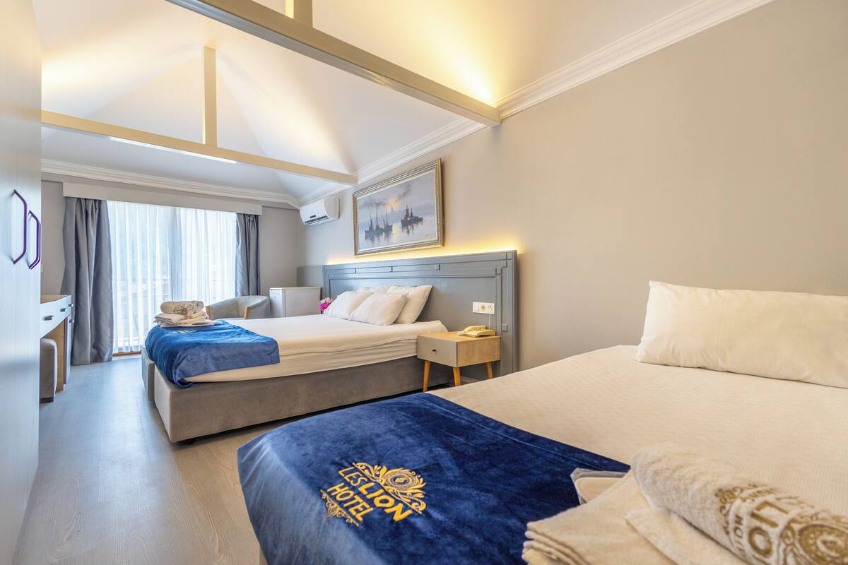 A hotel room with two beds, a desk, and a chair.
