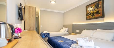 Ein Hotelzimmer mit einem Holztisch, zwei Betten, einem Gemälde und Blick auf den Flur.