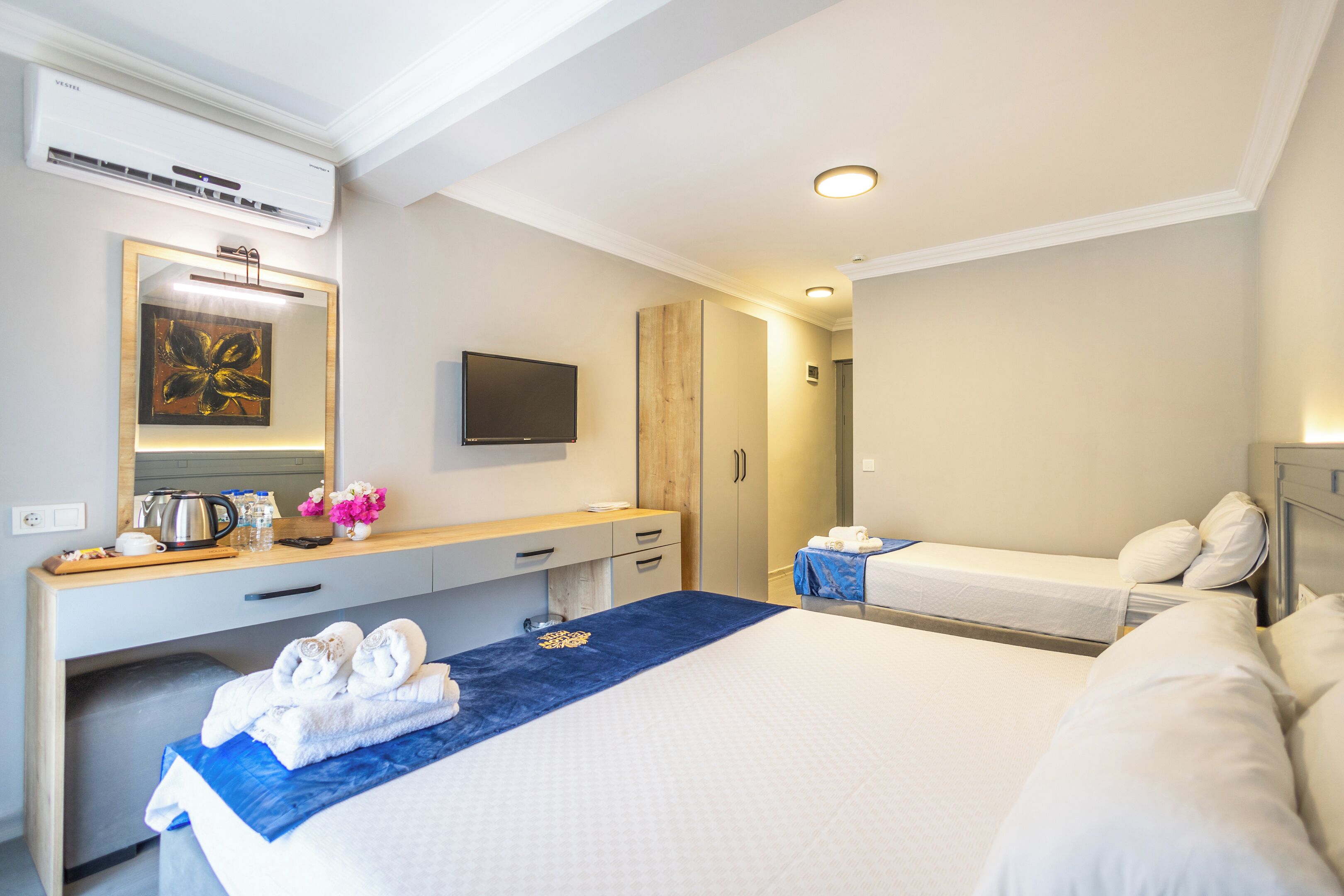 A hotel room with a large bed, a desk with a flat-screen TV, a wardrobe, and a bathroom.