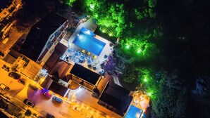 An aerial view of a hotel with a swimming pool, outdoor seating, and a well-lit entrance. - LESLION HOTEL TURUNC (Marmaris)