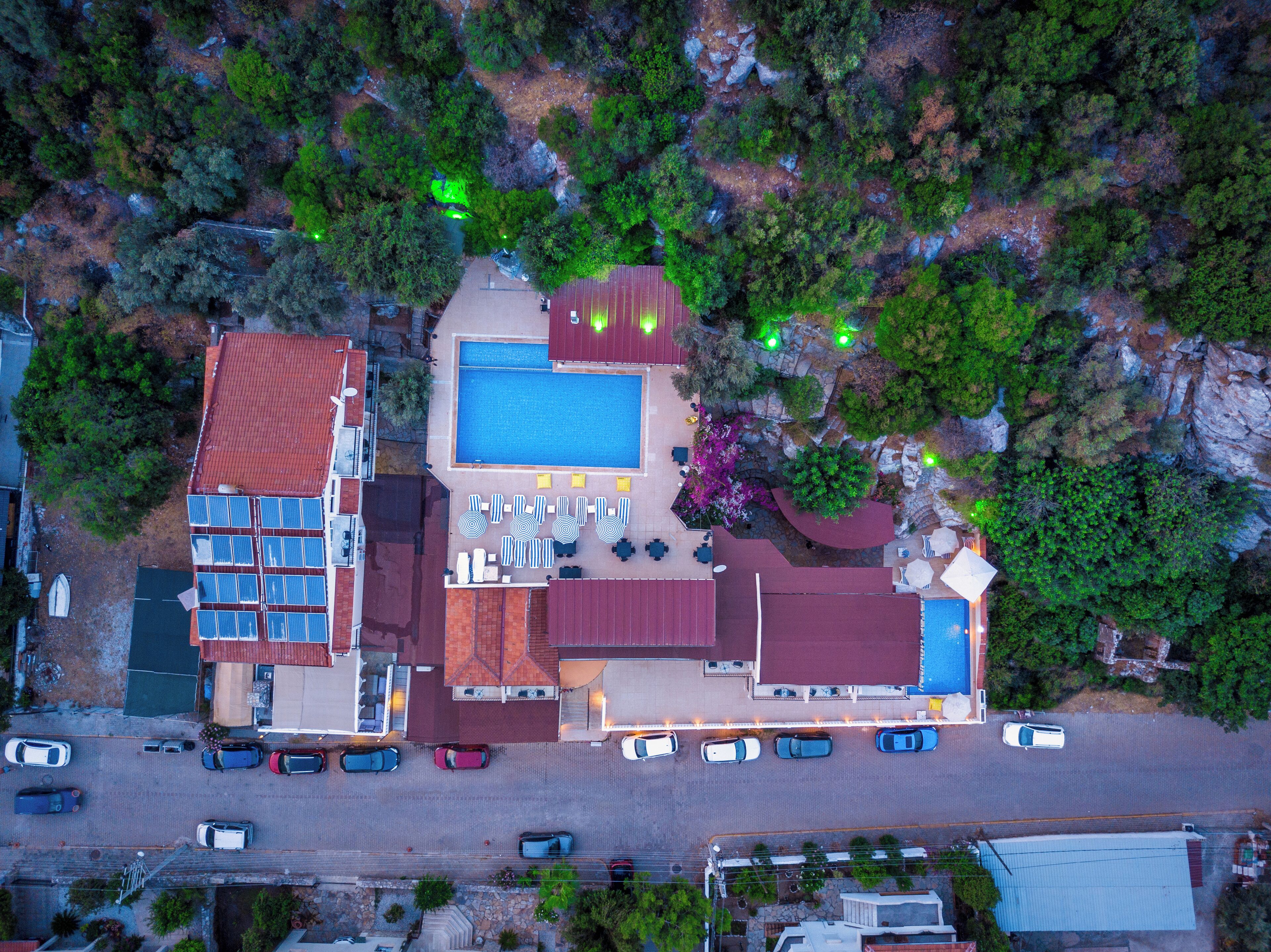 An aerial view of a hotel with a swimming pool, multiple lounge areas, and a parking lot.