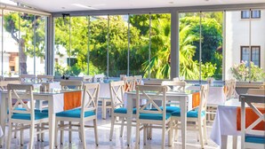 A restaurant with white tables and chairs, large windows with a view of greenery. - LESLION HOTEL TURUNC (Marmaris)