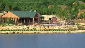 Un lodge sul lago con una terrazza coperta, pareti in pietra e un piccolo parco giochi.