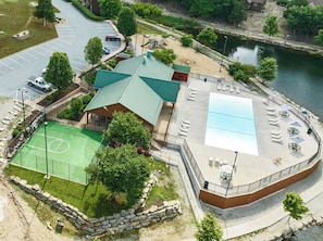 Vue aérienne d’un complexe de loisirs comprenant un terrain de sport, une piscine et un espace de repos couvert.