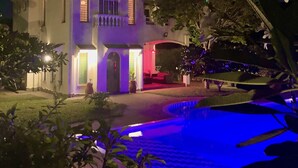 Um edifício com vários andares, área de piscina, espaço para sentar ao ar livre e entrada bem iluminada.