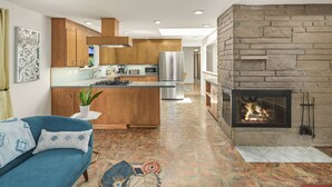 A modern kitchen with a central island, stainless steel appliances, and a stone fireplace. - Mid century modern retreat w/ expansive garden and central A/C (Lake Forest Park)