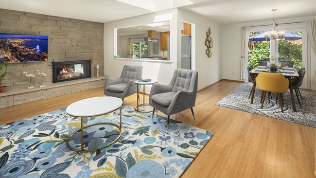 A modern living room with a fireplace, a flat-screen TV, and a dining area with a yellow chair. - Mid century modern retreat w/ expansive garden and central A/C (Lake Forest Park)