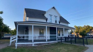 A two-story house with a covered porch and a black fence. - Experience Sturgatory 1BR by Main & Junction (Sturgis)