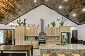 A spacious kitchen with wooden cabinets, a large island, and a stone backsplash.