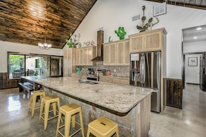 A spacious kitchen with a large island, wooden cabinets, and stainless steel appliances.