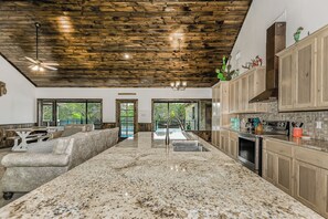 A spacious kitchen with granite countertops, wooden cabinets, and a large island.