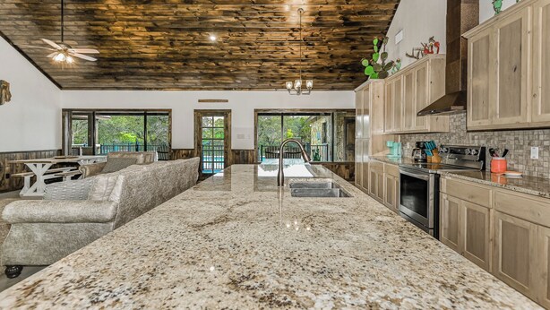 A spacious kitchen with granite countertops, wooden cabinets, and a large island. - Prickly Pear, Pool, Golf Course Home, @ Frio River Vacation Rentals (Concan)