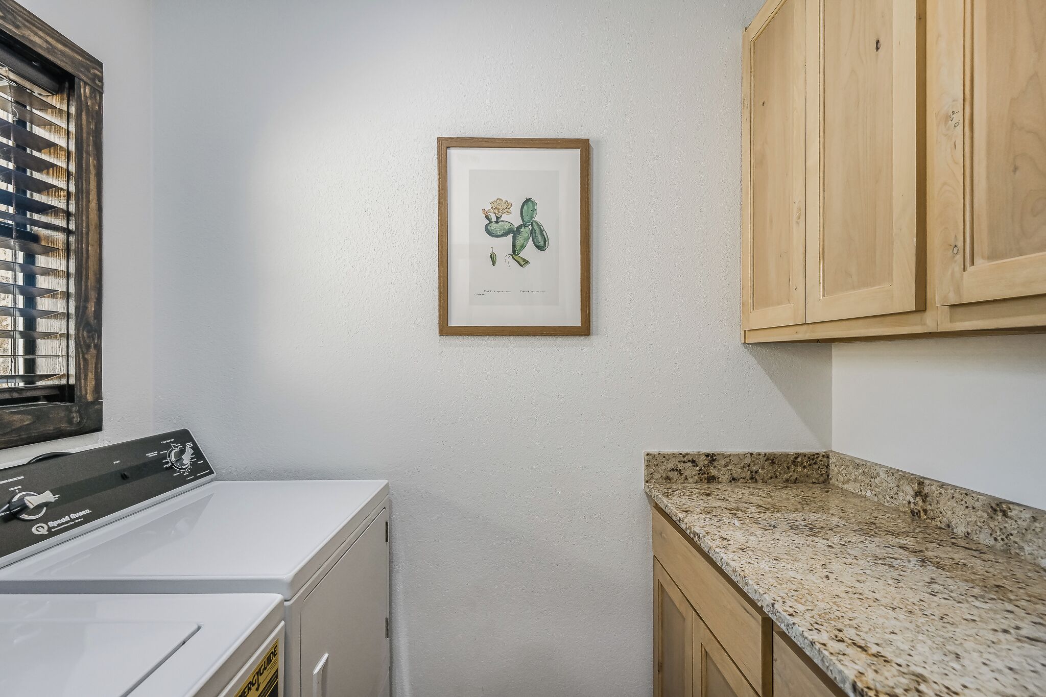 A laundry area with a washing machine, a countertop, and wooden cabinets.