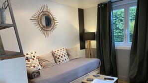 Een moderne slaapkamer met een houten bed, een ronde spiegel, een staande lamp en uitzicht op groen door een raam.