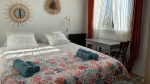 Een slaapkamer met een bed, twee spiegelwanden, een bureau en een stoel.