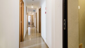 Pasillo de hotel con puertas de madera, suelo de baldosas y señal de salida visible.