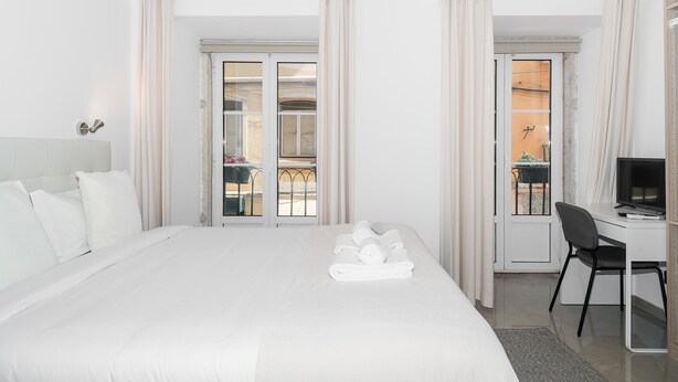 Habitación de hotel con una cama, un escritorio, una silla y vistas por la ventana.