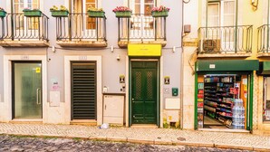 Un edificio con puertas numeradas, una puerta verde y una tienda que vende agua embotellada.