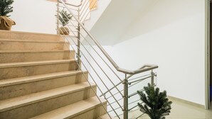 Una escalera con barandillas metálicas, un pequeño árbol de Navidad y un cuadro en la pared.