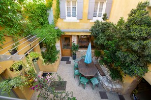 A courtyard with a table and chairs, surrounded by potted plants and a stone wall. - Gîte de L'aspa (Saint-Christol)