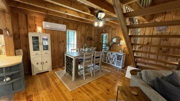 A wooden cabin interior with a kitchen, dining area, and a living room.