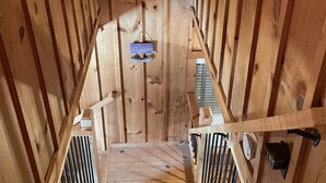 Un interior de madera con una escalera que lleva a una zona tipo cabaña.