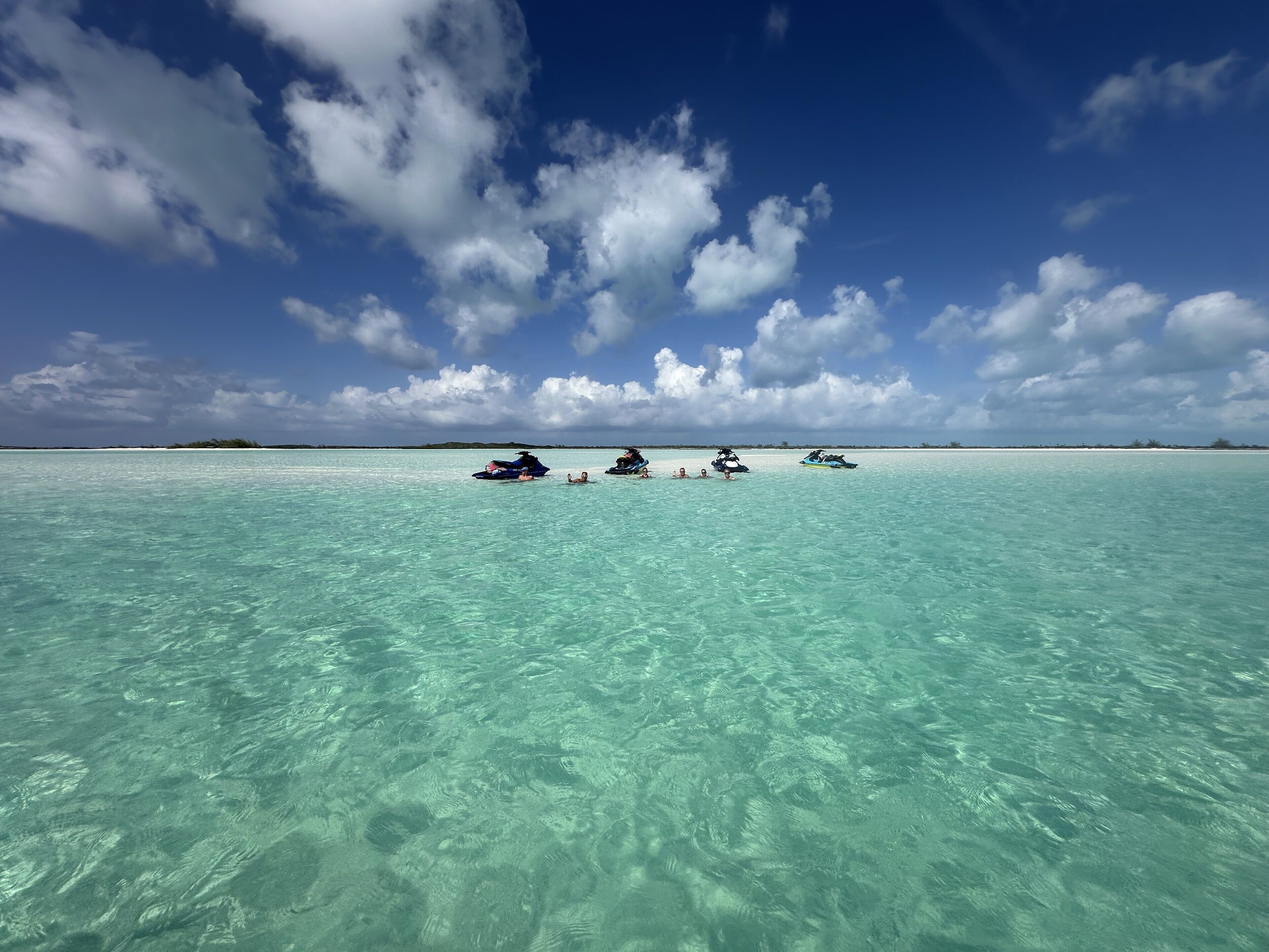 Une mer turquoise et limpide, avec des jet-skis et des personnes dans l’eau.