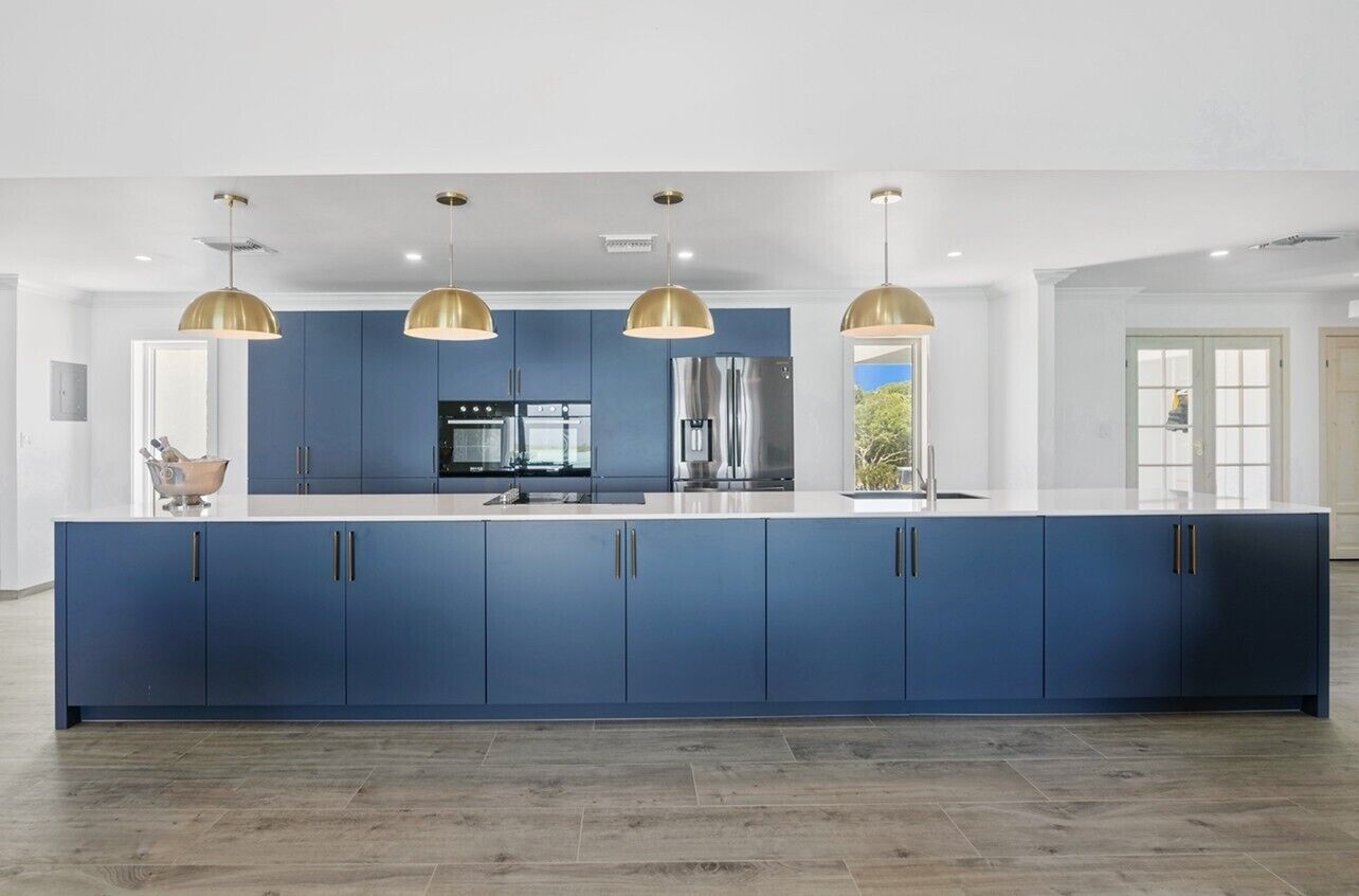 A modern kitchen with blue cabinets, a central island, and pendant lighting.