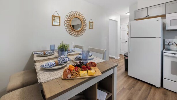 A modern kitchen with white cabinets, a built-in oven, and a countertop with a fruit and cheese board. - Family Friendly & Cheerful Blue Jay Ranch House close to KSU stadium  (Manhattan)