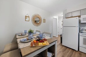 A modern kitchen with white cabinets, a built-in oven, and a countertop with a fruit and cheese board. - Family Friendly & Cheerful Blue Jay Ranch House close to KSU stadium  (Manhattan)