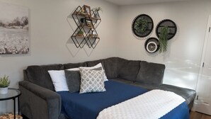 A modern living room with a gray sectional sofa, a blue accent wall, and decorative wall art. - Family Friendly & Cheerful Blue Jay Ranch House close to KSU stadium  (Manhattan)