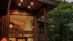 Een modern houten huis met een glazen voordeur, een balkon en een keurig onderhouden tuin.