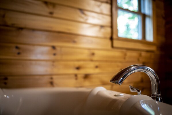 A bathroom with a wooden wall and a white bathtub.