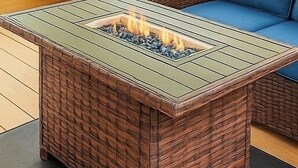 Eine Holzterrasse mit einem Feuerkorb und einer blauen, gepolsterten Sitzgruppe.