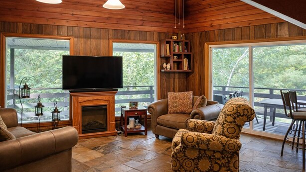 A cozy living room with a fireplace, leather sofas, a television, and a bookshelf.