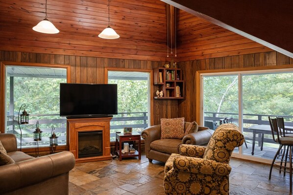 A cozy living room with a fireplace, leather sofas, a television, and a bookshelf.