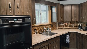 A modern kitchen with dark wood cabinets, a built-in oven, and a large window.