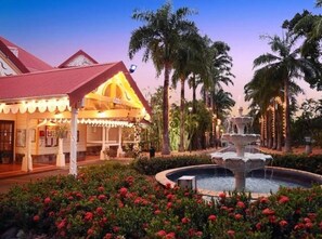 Stunning hotel with a red-tiled roof and beautifully maintained garden featuring a central fountain.