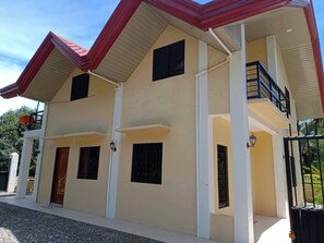 A two-story building with a flat roof, white exterior walls, and a balcony on the upper floor.