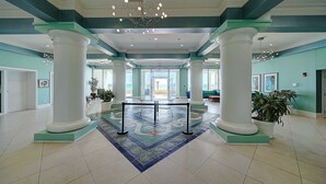 Un hall d’entrée spacieux avec un espace salon central, de grandes colonnes et un tapis à motifs.