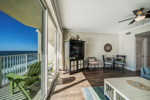 Un balcon avec vue sur l’océan, un coin repas avec une table et des chaises, et un ventilateur de plafond.