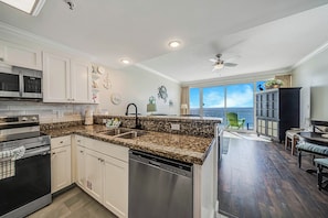 A modern kitchen with white cabinets, granite countertops, stainless steel appliances, and a dishwasher. - FREE Perks! Boardwalk 1907, King Master, New Walk In Shower & Heated Pool! (Panama City Beach)