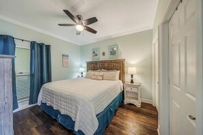 Une chambre à coucher avec un lit, un ventilateur de plafond, une table de chevet et une porte.