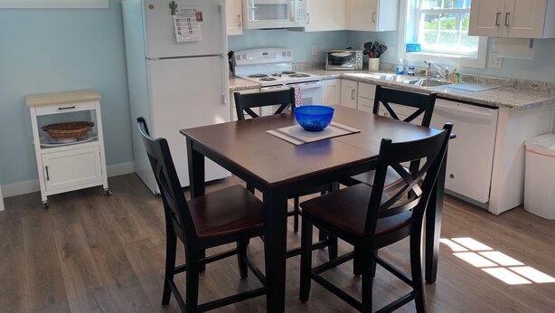 A modern kitchen with white cabinets, a wooden dining table, and a blue bowl on the table.
