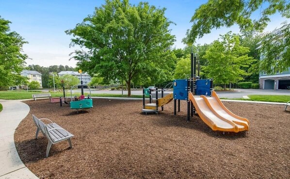 Un parque infantil con tobogán, estructuras para escalar y un banco.