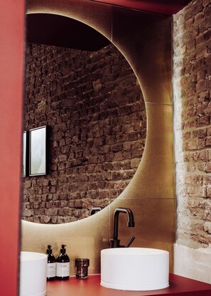 Experience the unique blend of rustic and contemporary style in this bathroom, featuring a curved wall, round sink, and sleek faucet.
